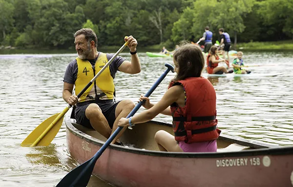 Father and daughter using paddle boat together