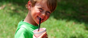 Camper smiling at camera while drinking with straw