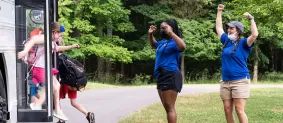 Camp directors cheering on campers as they exit bus